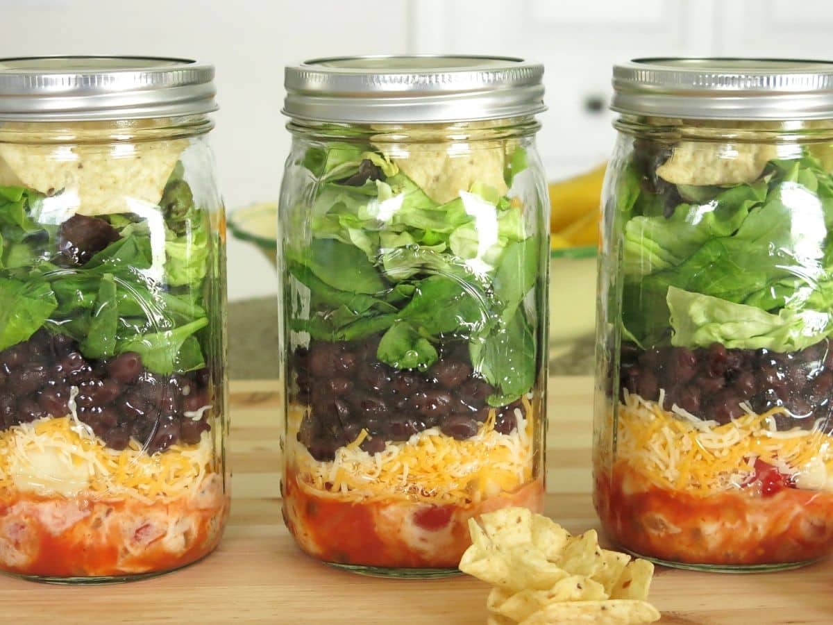 Three mason jar taco salads on a counter.