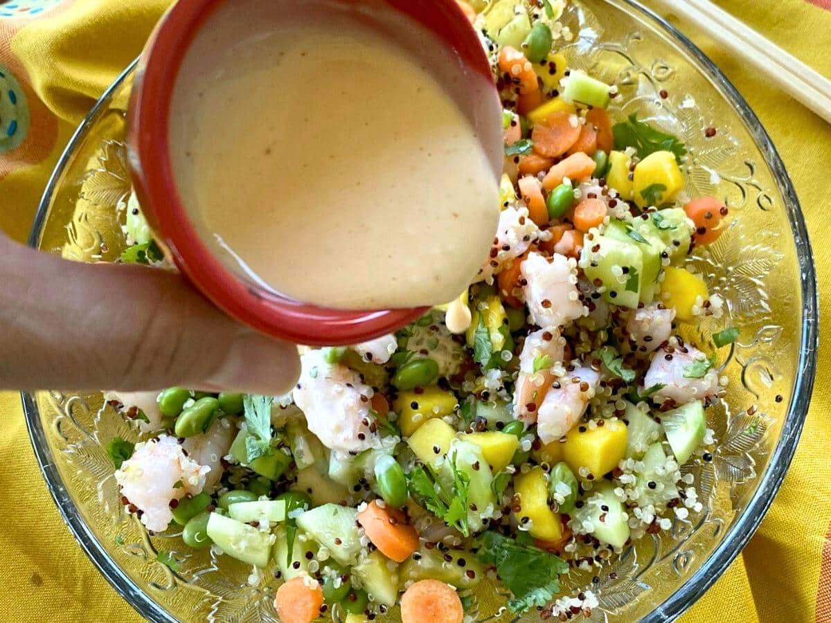 Creamy poke sauce being poured over a shrimp poke bowl.