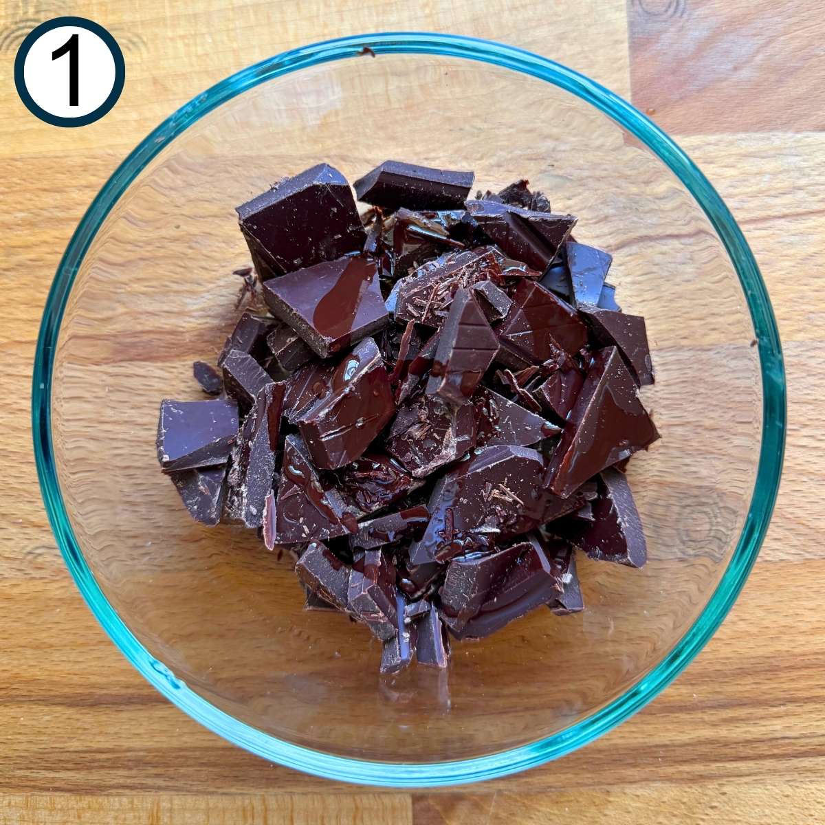 Chopped chocolate and oil in a glass bowl.