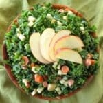 Kale apple slaw with honey mustard dressing in a bowl with apple slices fanned on top.