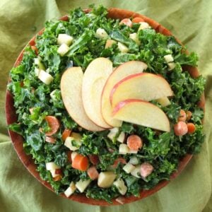 Kale apple slaw with honey mustard dressing in a bowl with apple slices fanned on top.