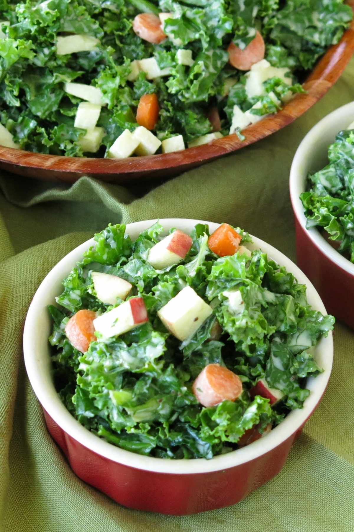 Small red bowl is Tropical Smoothie kale apple slaw with a larger bowl of the salad behind it.