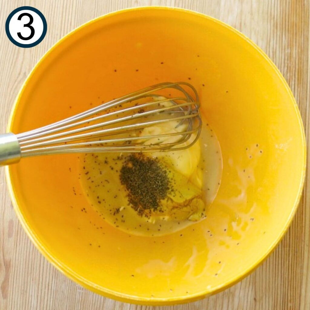 Yellow bowl with unmixed honey mustard ingredients and a whisk.