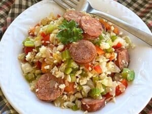 Dirty cauliflower rice with Andouille sausage in white bowl with a fork