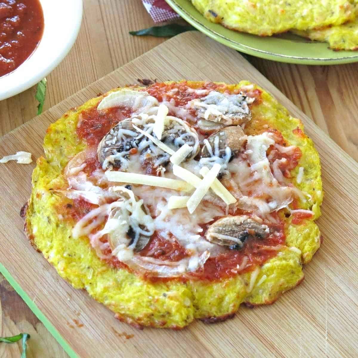 Spaghetti squash pizza crust cooked until crispy and topped with sauce, mushrooms, and cheese.