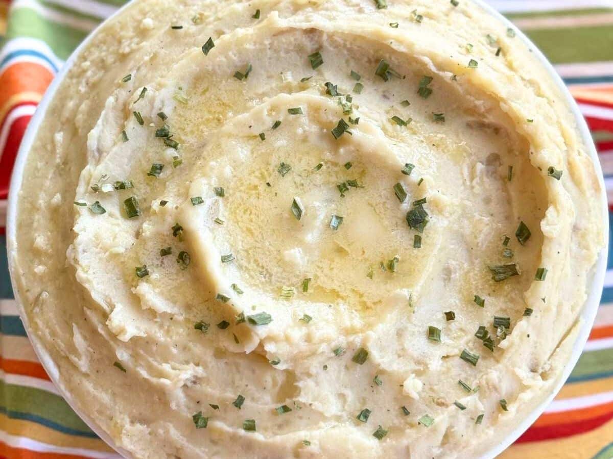 White bowl with crockpot mashed potatoes with butter pooling in the center.