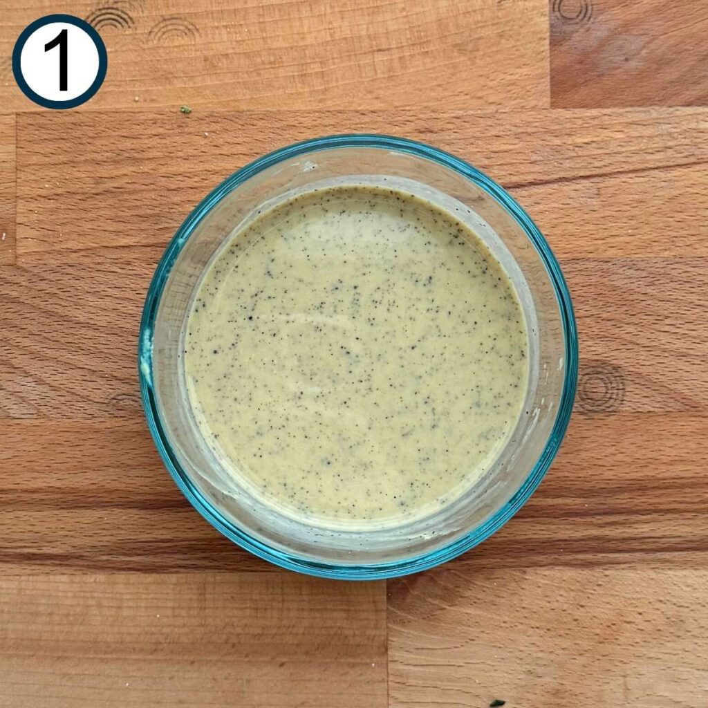 Lemon juice, mustard, and black pepper mixed together in a glass bowl.