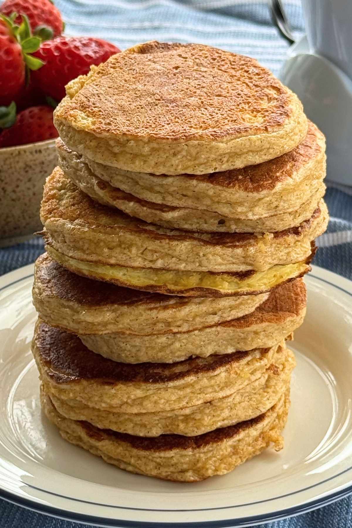 Stack of ten cottage cheese and oat pancakes on a plate.