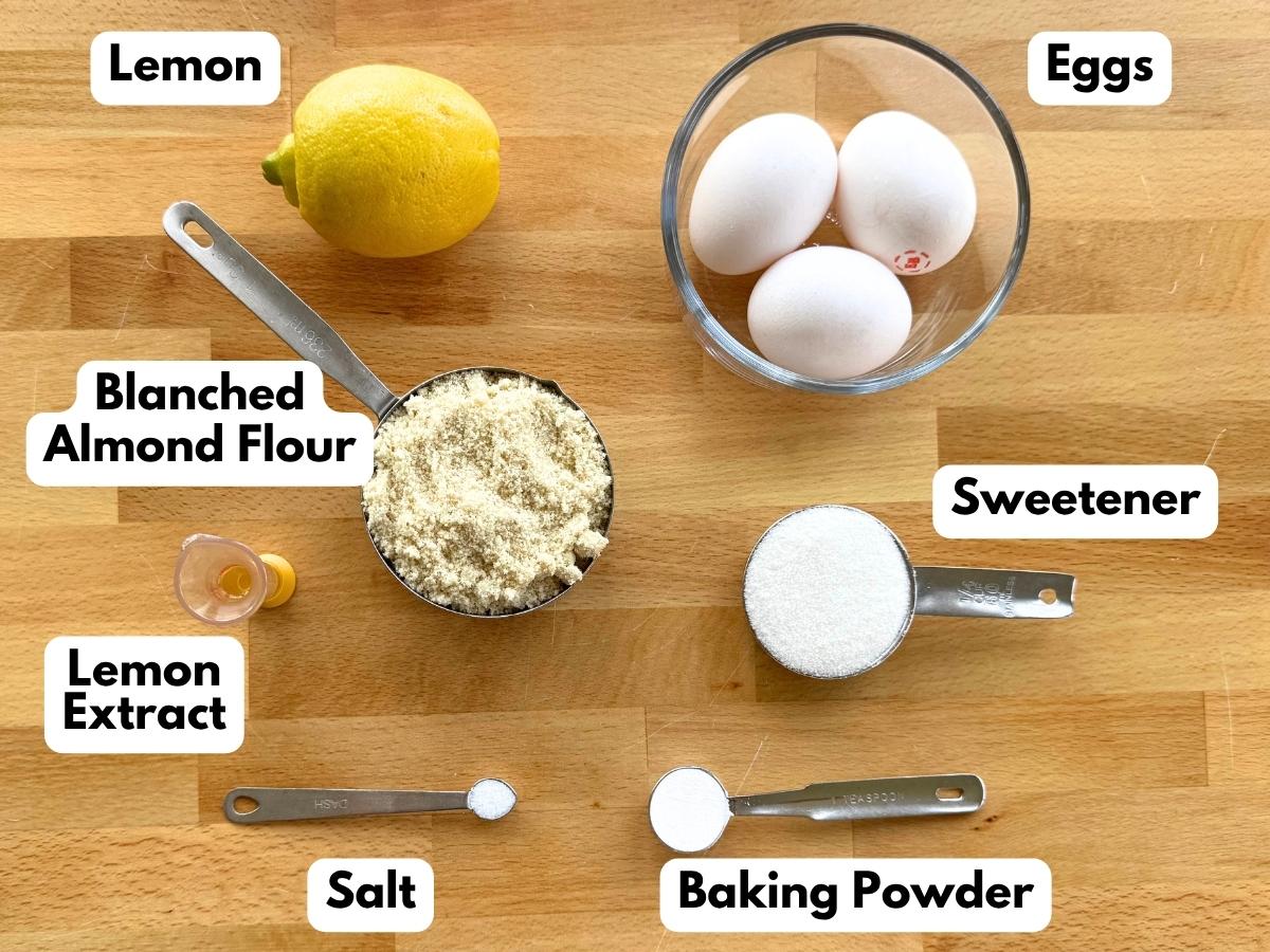 Labeled ingredients to make flourless lemon almond cake: a lemon, 3 eggs, almond flour, stevia, lemon extract, salt, and baking powder.