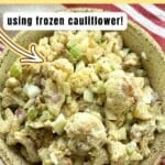 Light brown bowl with roasted cauliflower potato salad made with frozen cauliflower mixed with hard boiled eggs, chopped celery, and dill pickle relish.
