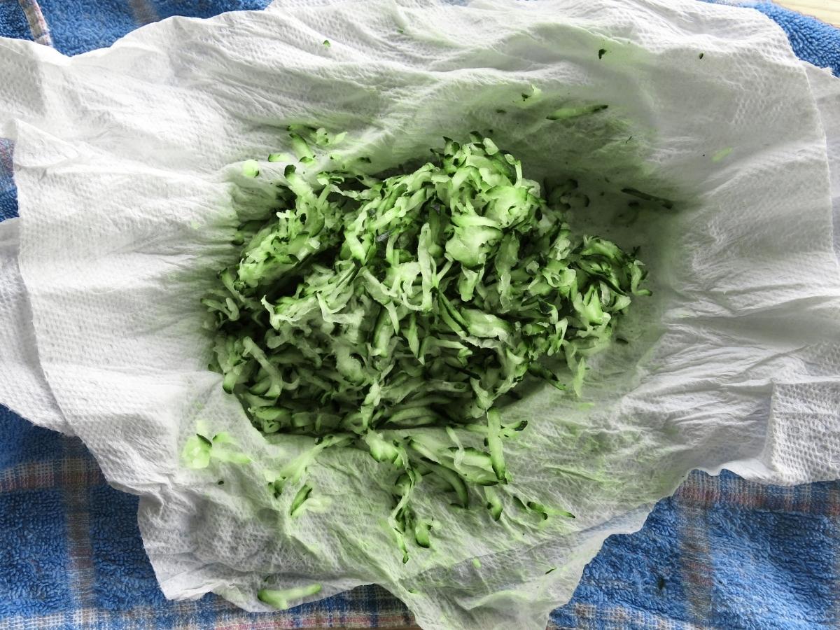 Zucchini that has been compressed to remove excess moisture on top of paper towels and a blue towel.