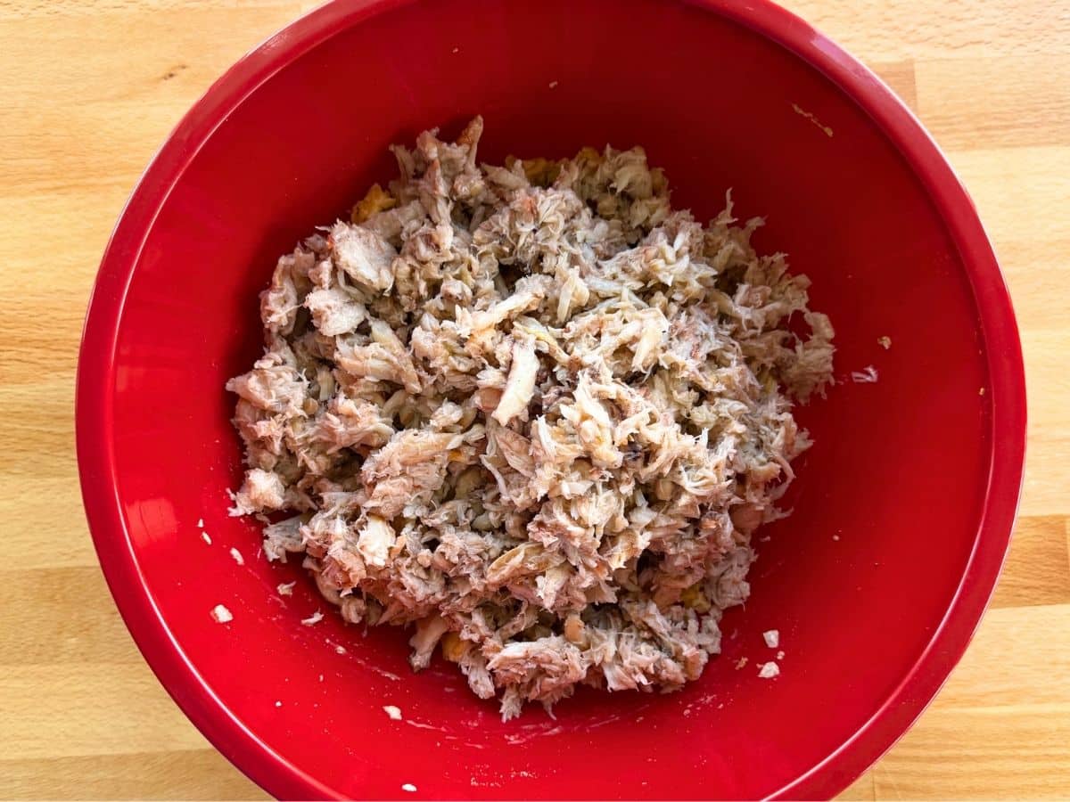 Lump crab, broken into chunks and folded into binder ingredients in a red bowl.