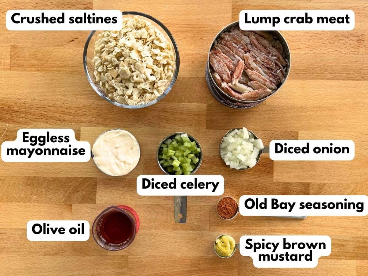 Ingredients to make eggless crab cakes: lump crab meat, crushed saltines, eggless mayonnaise, diced celery, diced onion, Old Bay seasoning, spicy brown mustard, and olive oil.