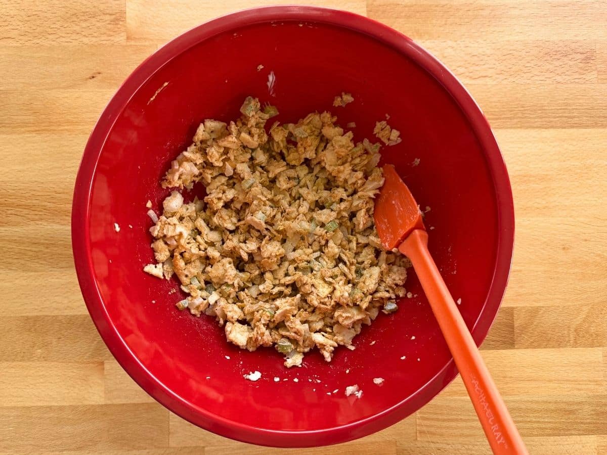 Binder ingredients with crushed saltines in a red bowl with a spatula.