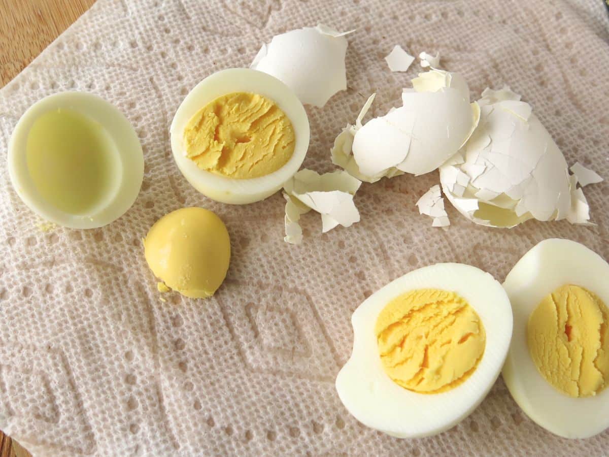 Hard-boiled eggs cut in half with egg shells in the background.