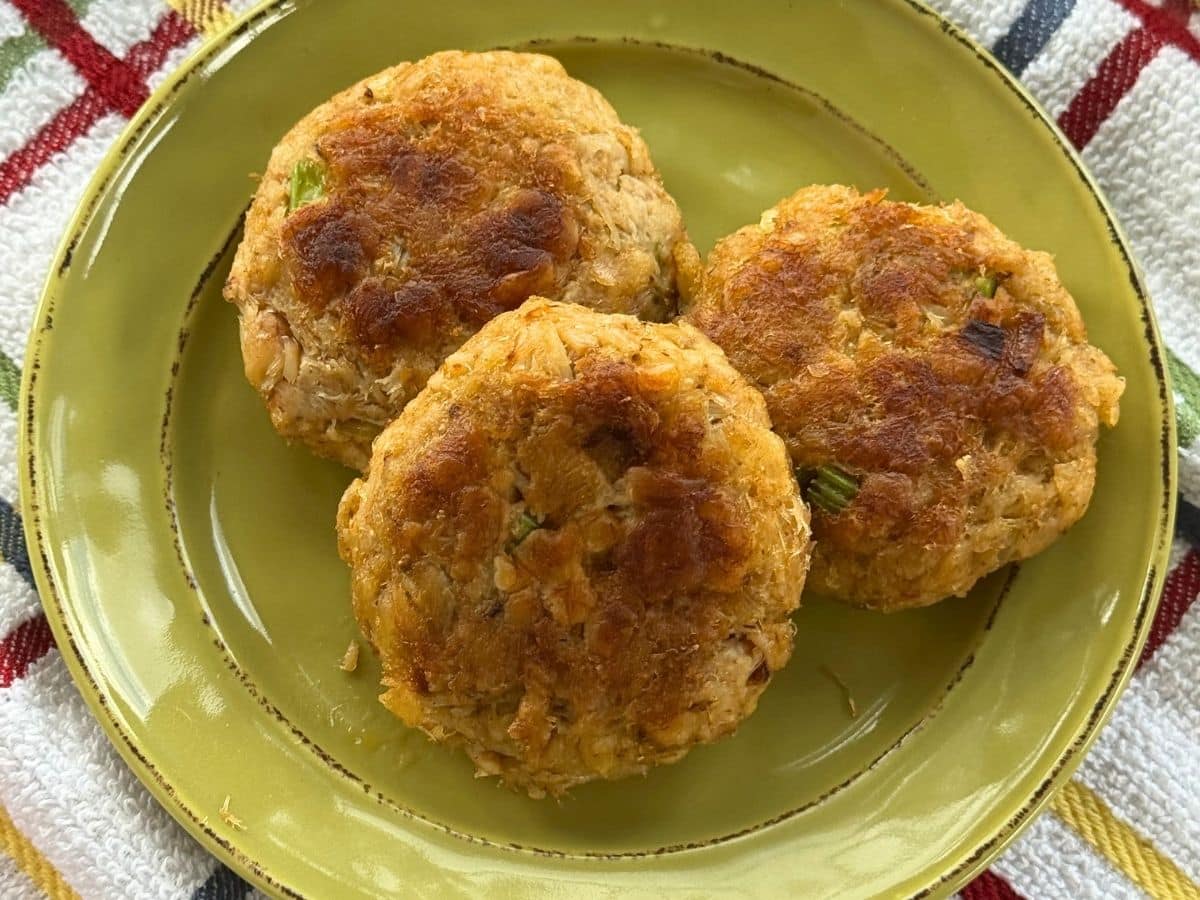 Three Maryland crab cakes on a green plate.