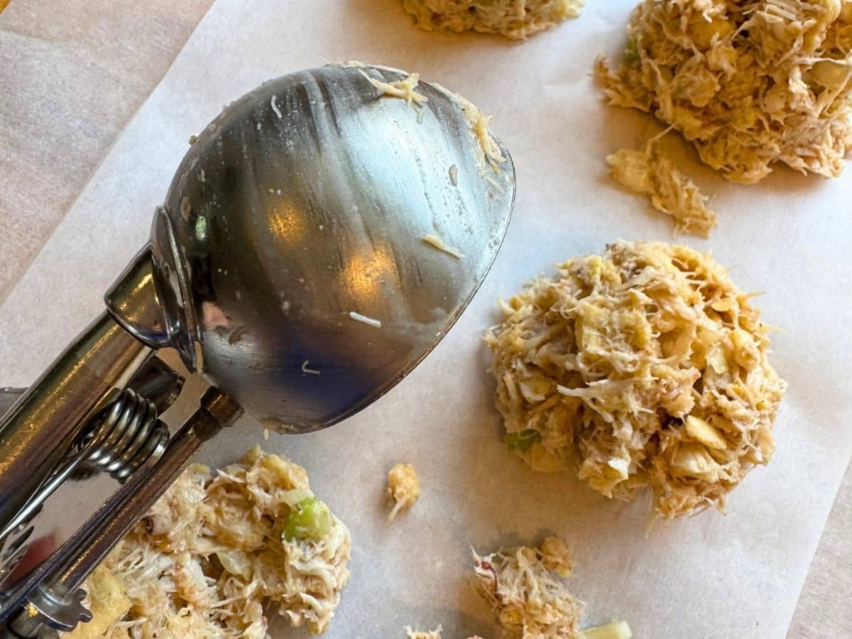 Disher scoop over uncooked crab cake mixture before it is compressed.