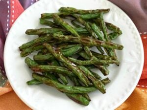 White plate with charred roasted green beans.