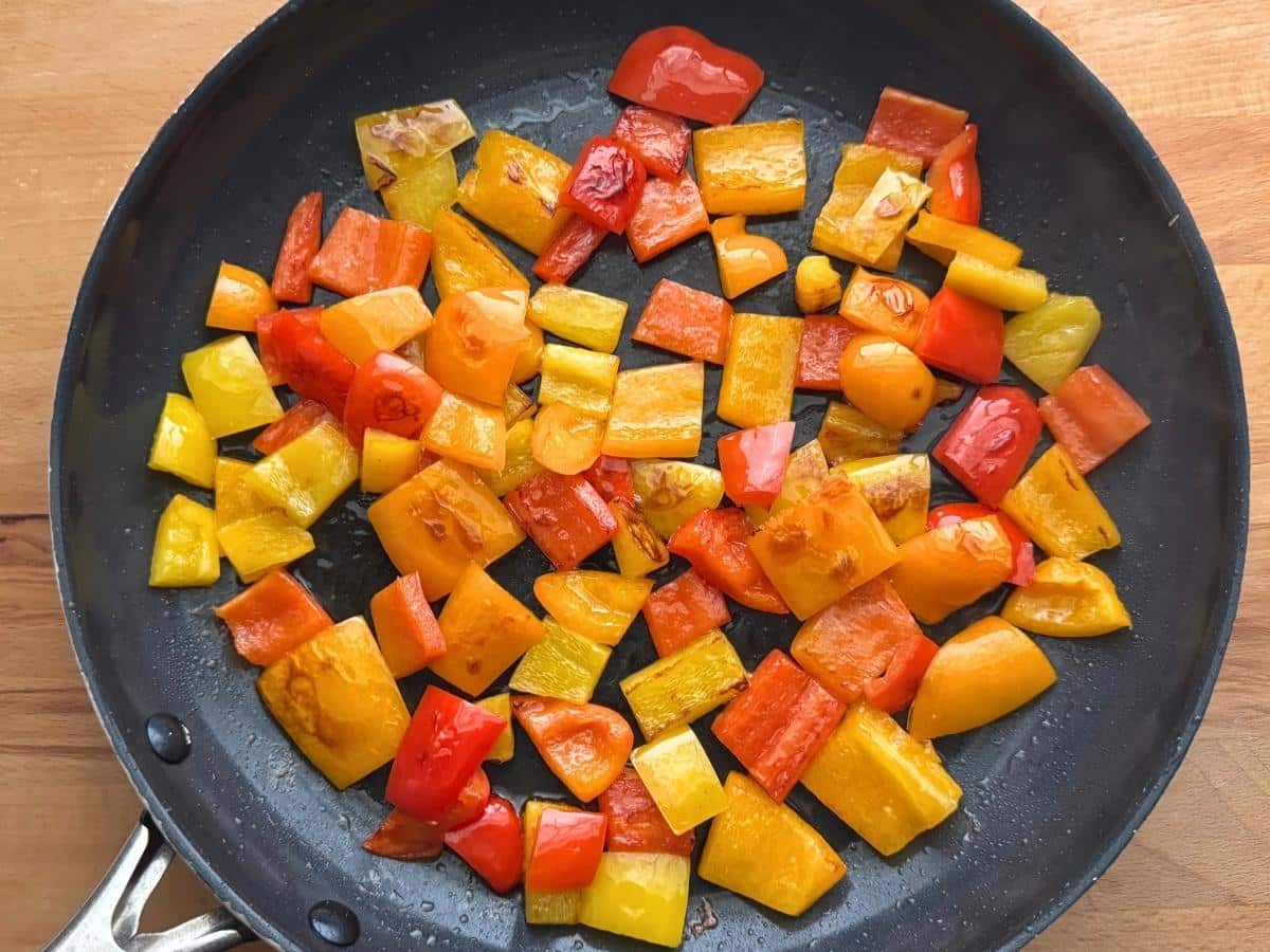 Lightly browned chopped red, orange, and yellow bell peppers in a skillet.