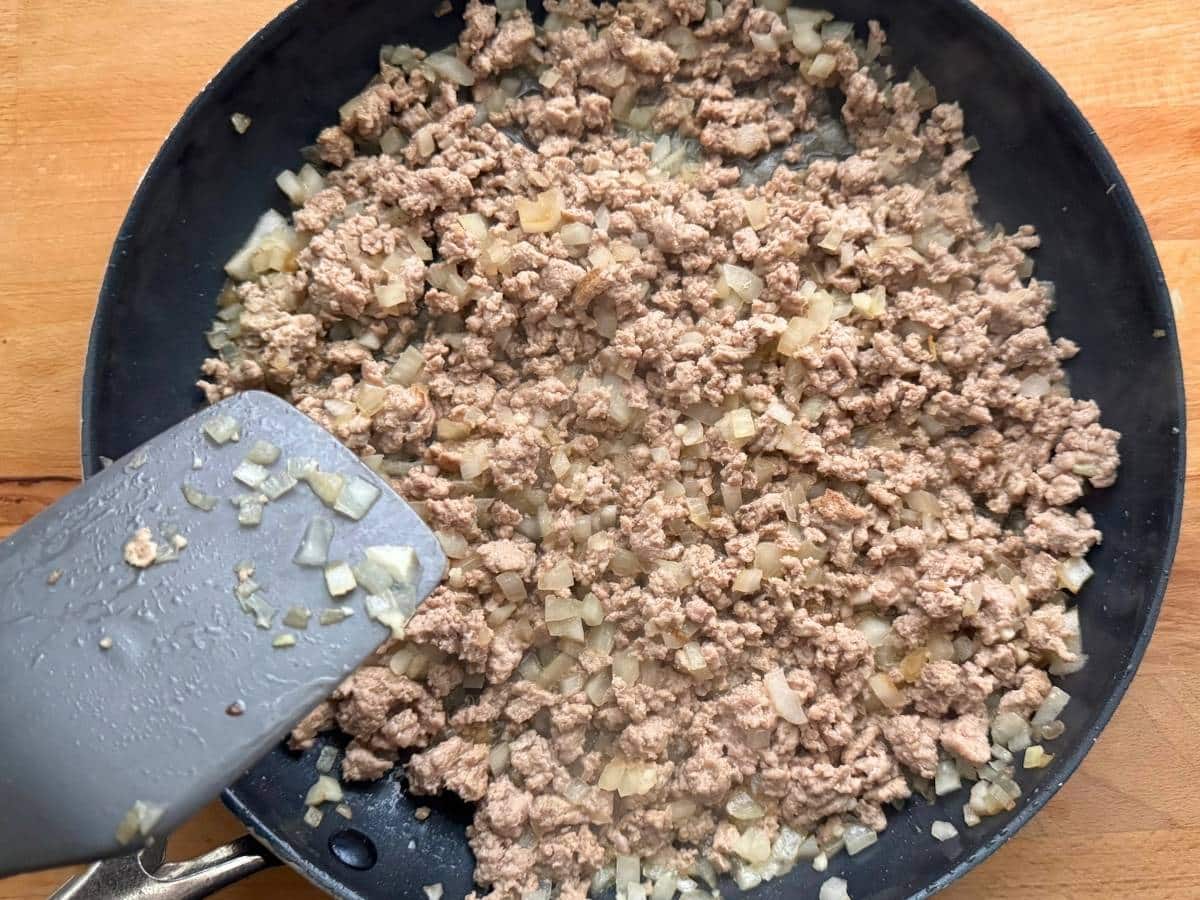 Cooked ground turkey with diced onion and garlic in a large skillet.