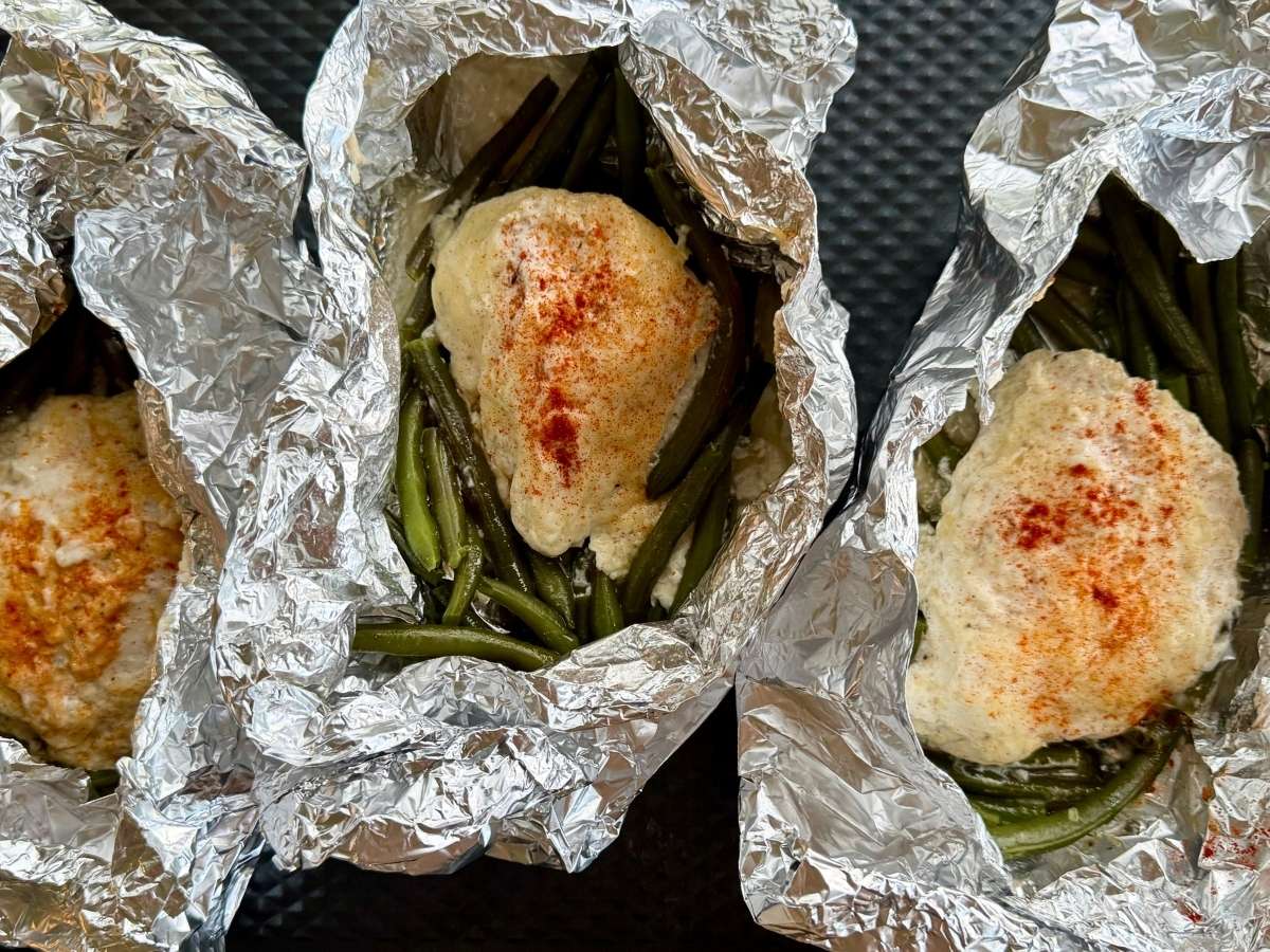Cooked ranch chicken inside open aluminum foil packets.