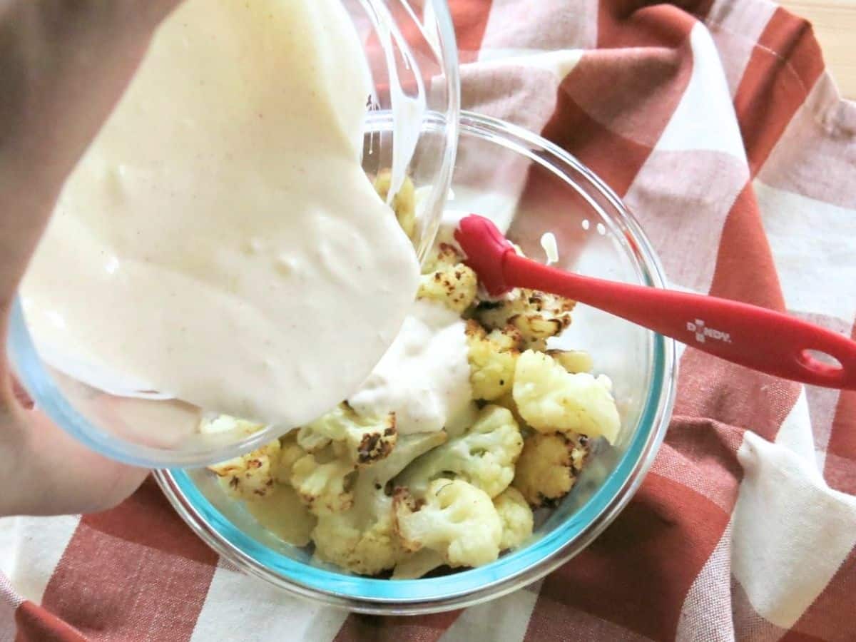 Lime cream being poured over roasted cauliflower.