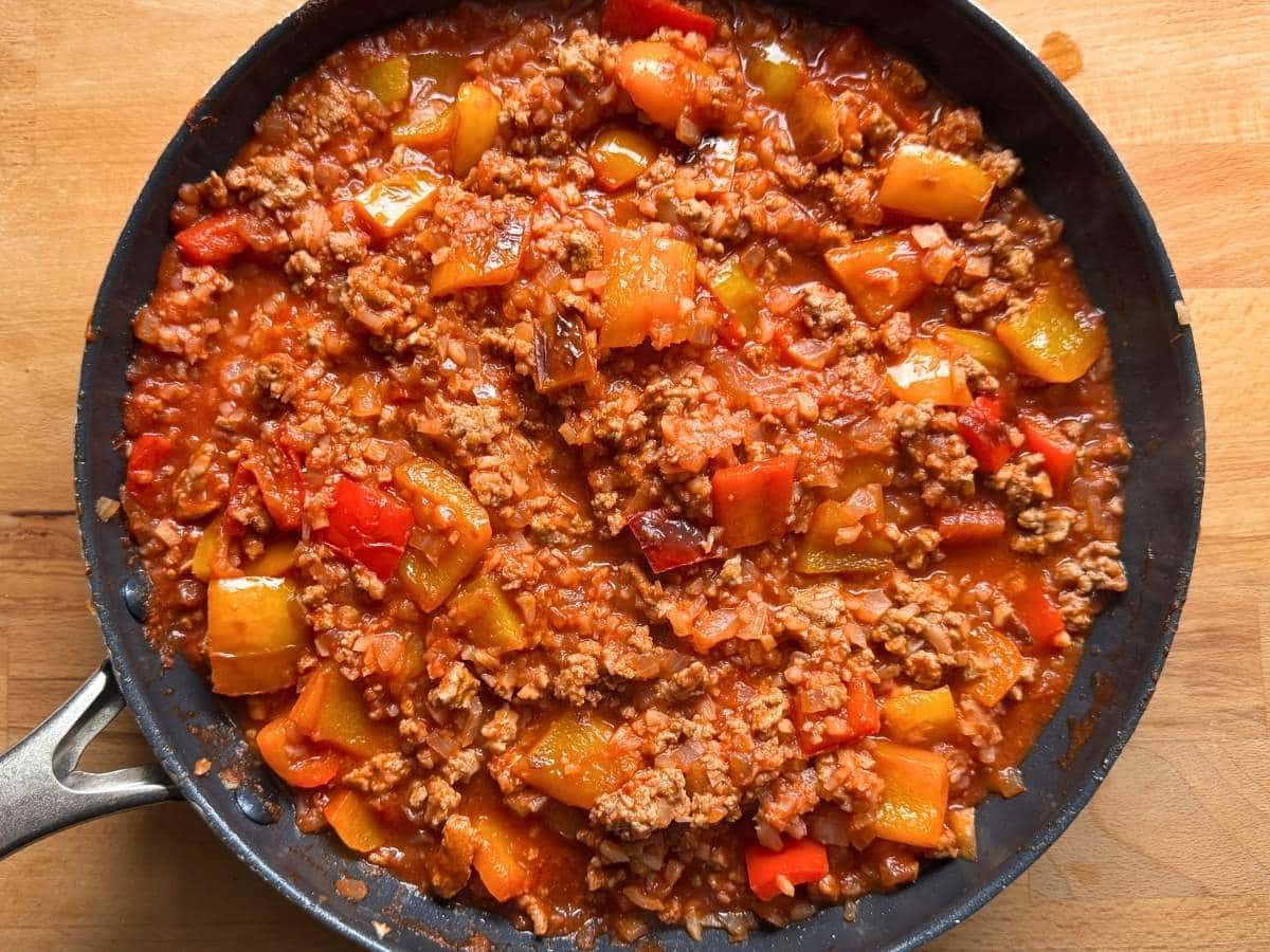 Ground turkey, bell peppers, tomato sauce, and cauliflower rice simmering together in a skillet.