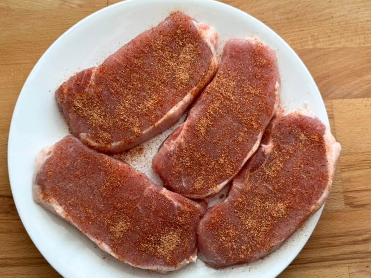 Four boneless, center-cut seasoned pork chops on a white plate.