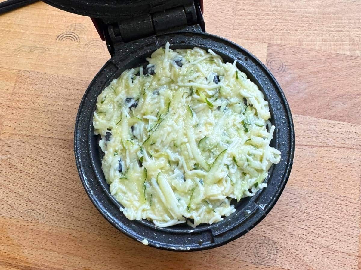 Zucchini waffle batter in a mini waffle maker.
