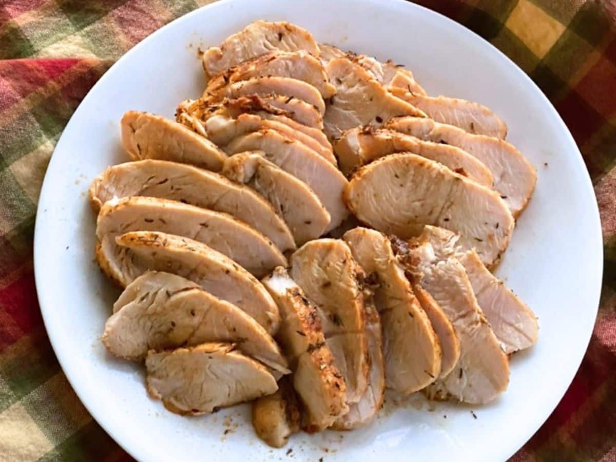 Sliced baked turkey tenderloin on a white plate.