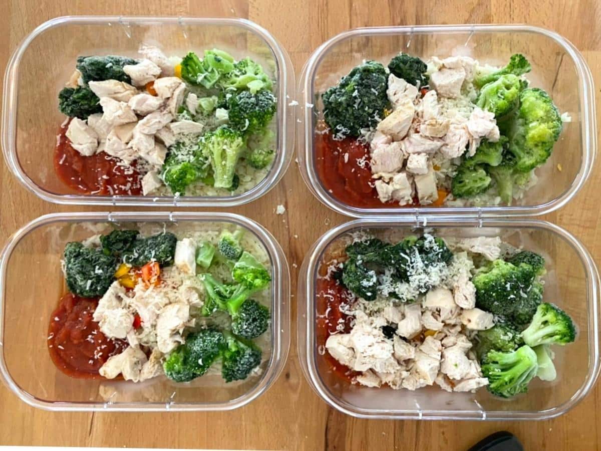 Chicken marinara meal prep bowls assembled with cauliflower rice, frozen vegetables, cooked chicken and Parmesan.