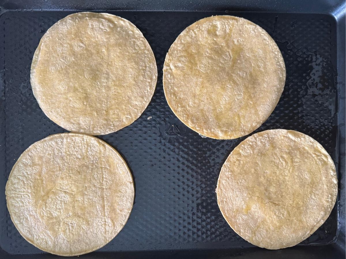 Ground chicken tacos arranged chicken-side down on an oiled baking sheet before baking.