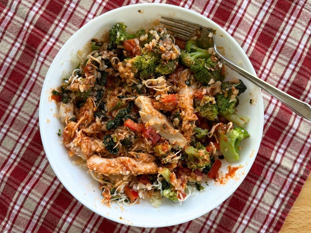 Low-carb chicken marinara bowl with cauliflower rice, broccoli, spinach, peppers and cheese.