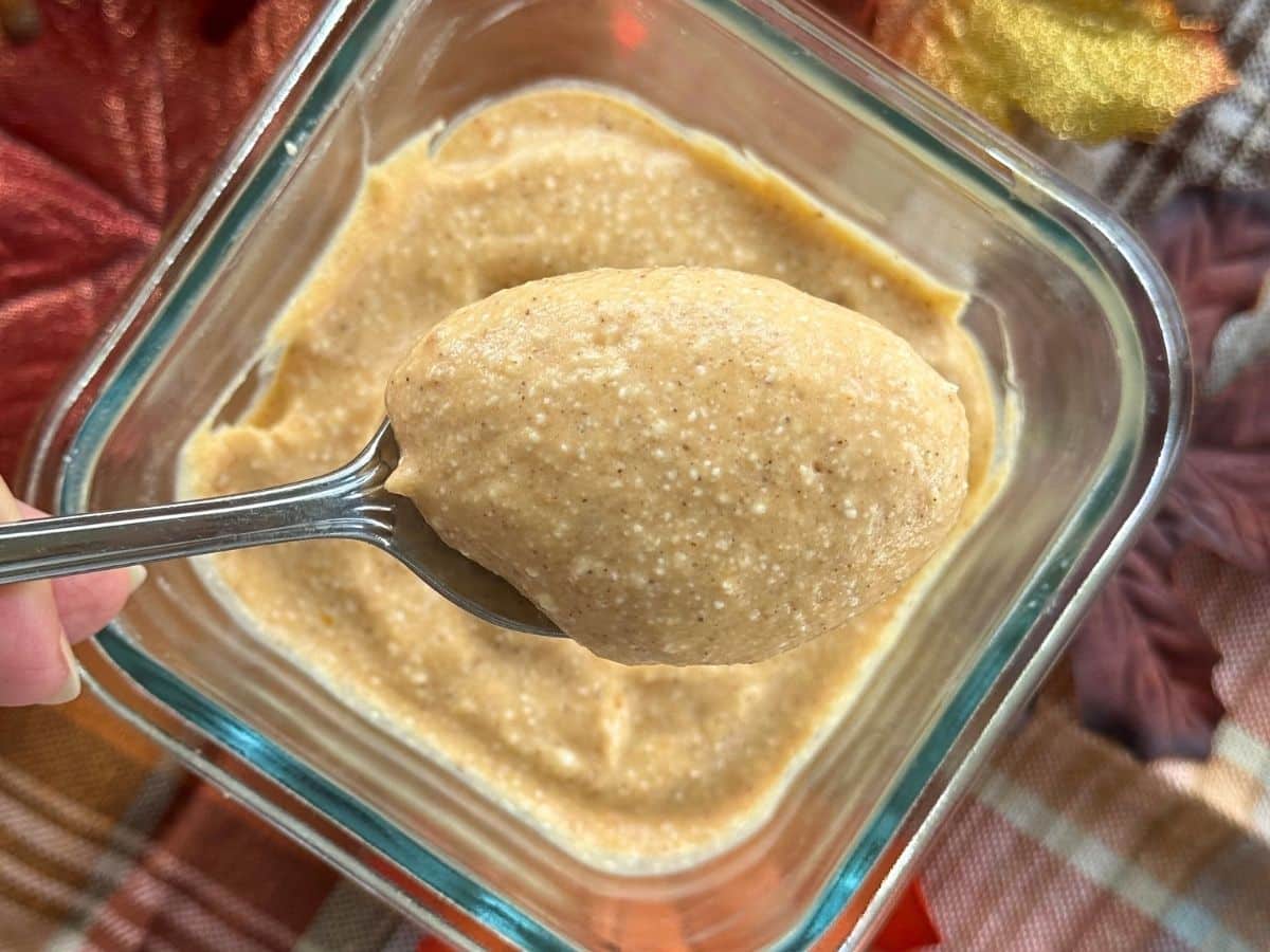 Spoon lifting whipped no-bake pumpkin cottage cheese dessert from container.