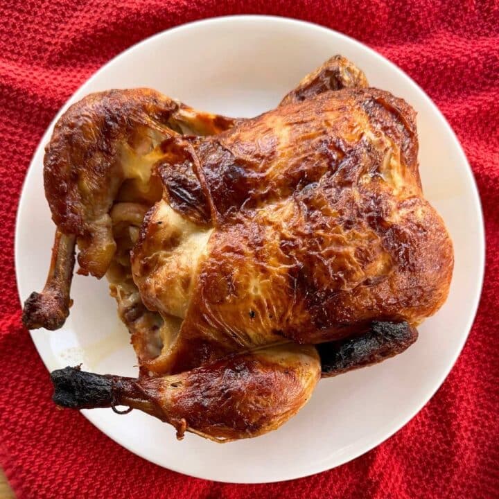 A whole rotisserie chicken on a white plate.