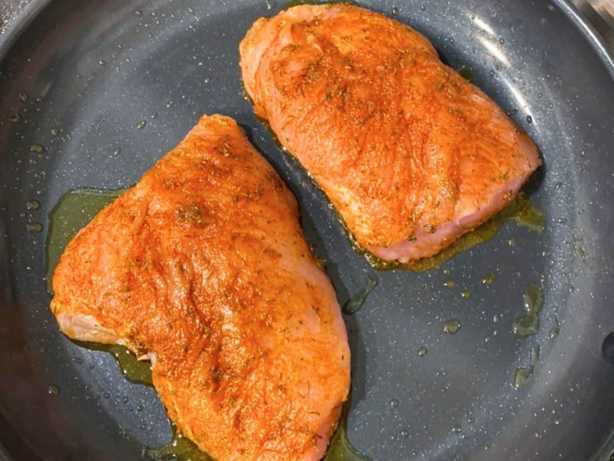 Two seared turkey breast tenderloins in a skillet.