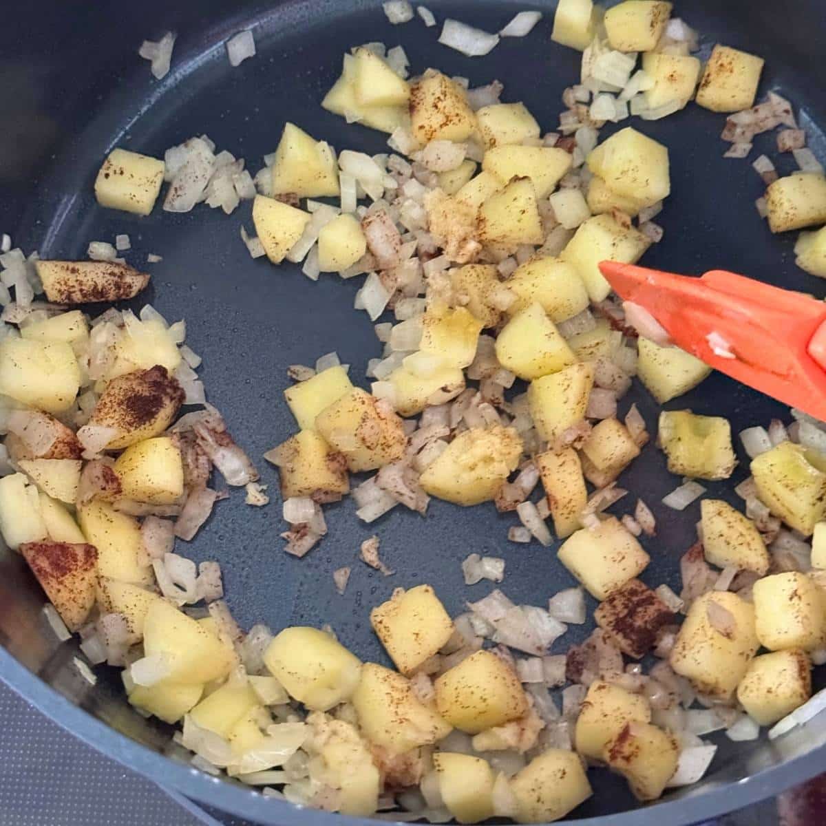 Cooking the diced apple and onion in olive oil until softened, then add the garlic and spices.