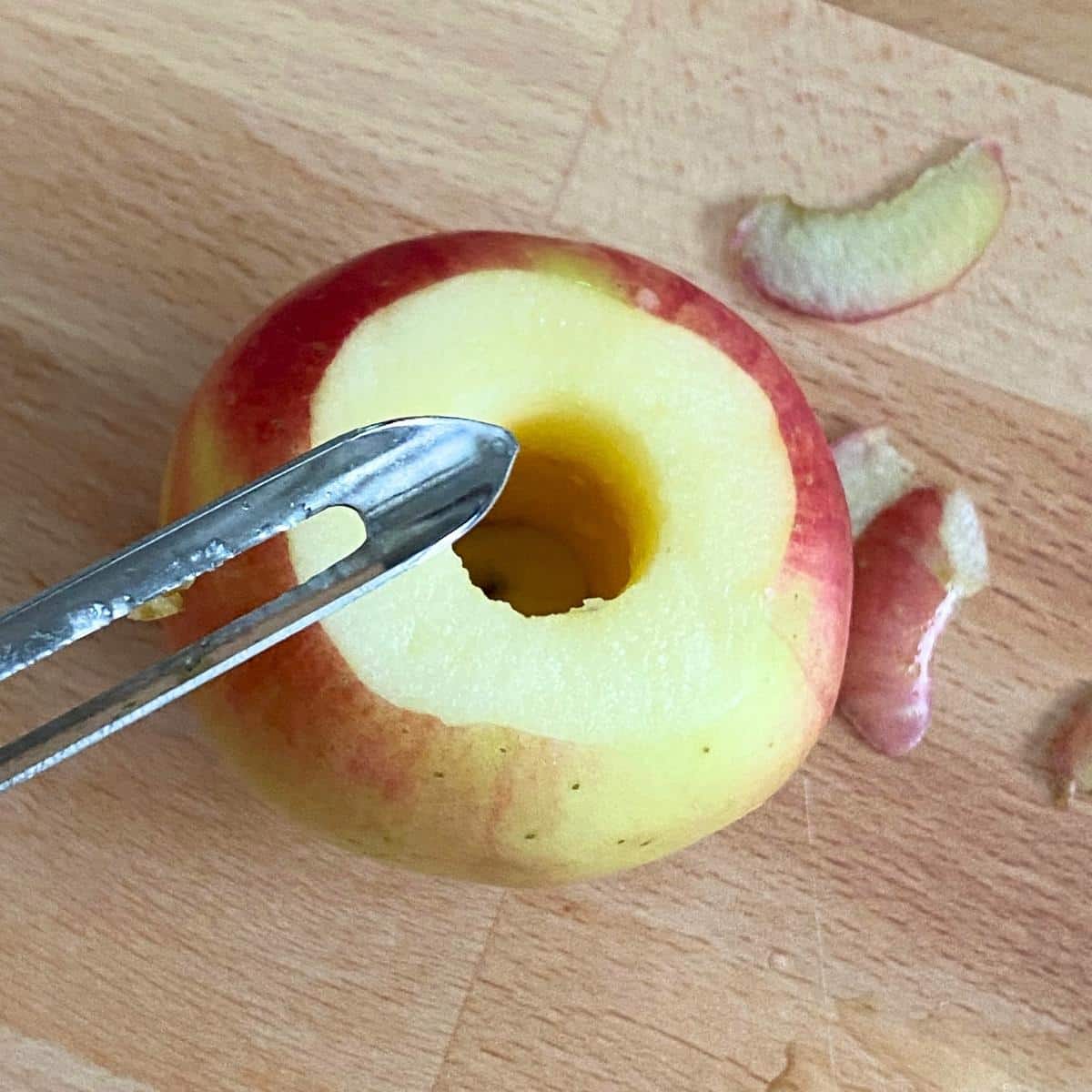 Cored apple with a vegetable peeler removing the area around the top.