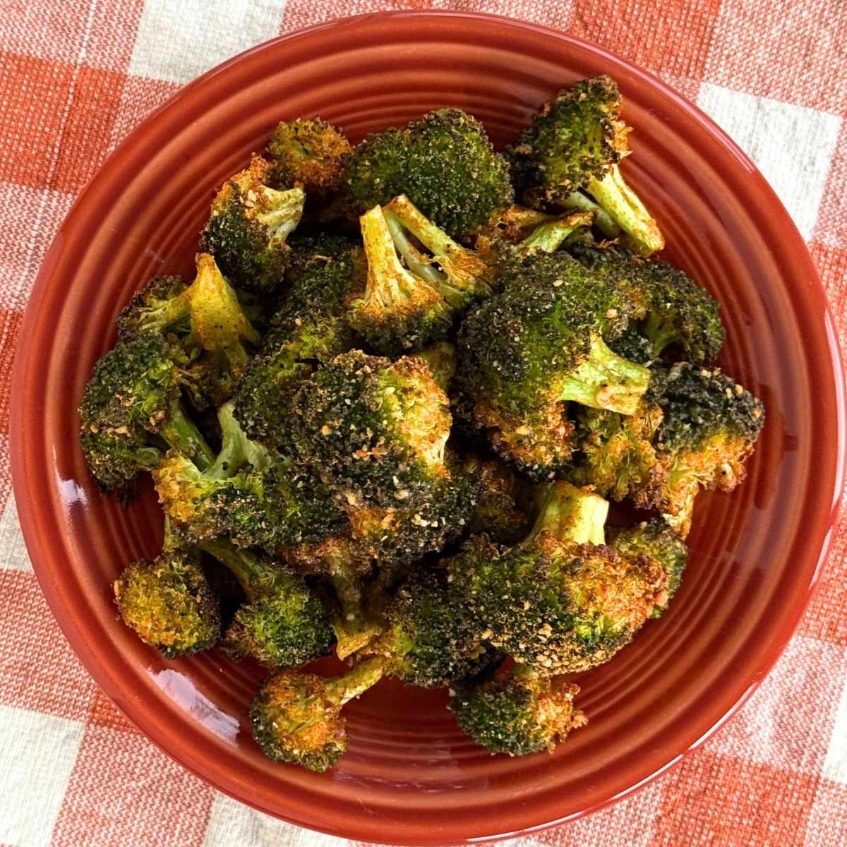 Crispy Parmesan broccoli bites with golden, roasted edges served in a red bowl.