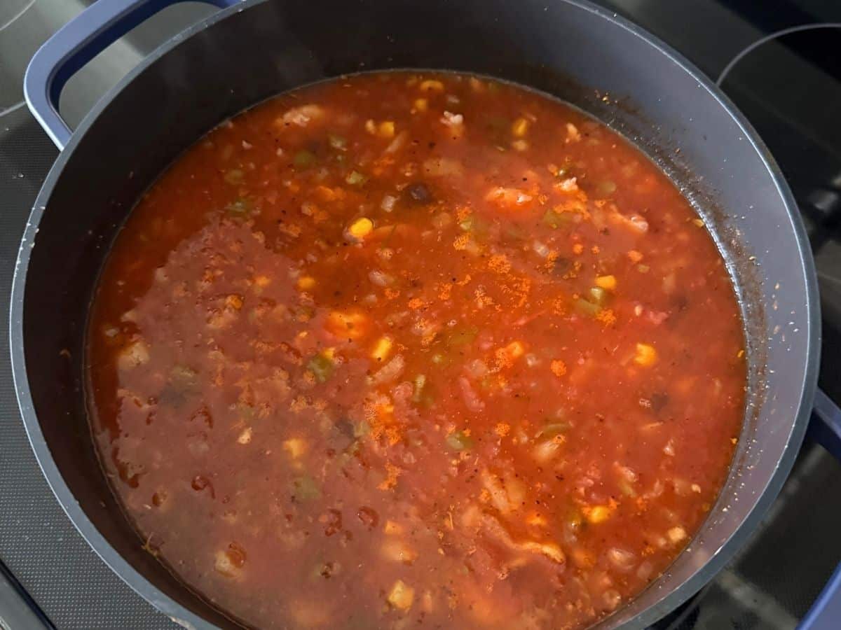 Tomatoes, black beans, corn, and green chiles simmering in broth for shrimp tortilla soup.