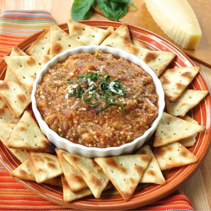 Eggplant Parmesan dip topped with fresh basil and Parmesan cheese and served warm with pita chips.