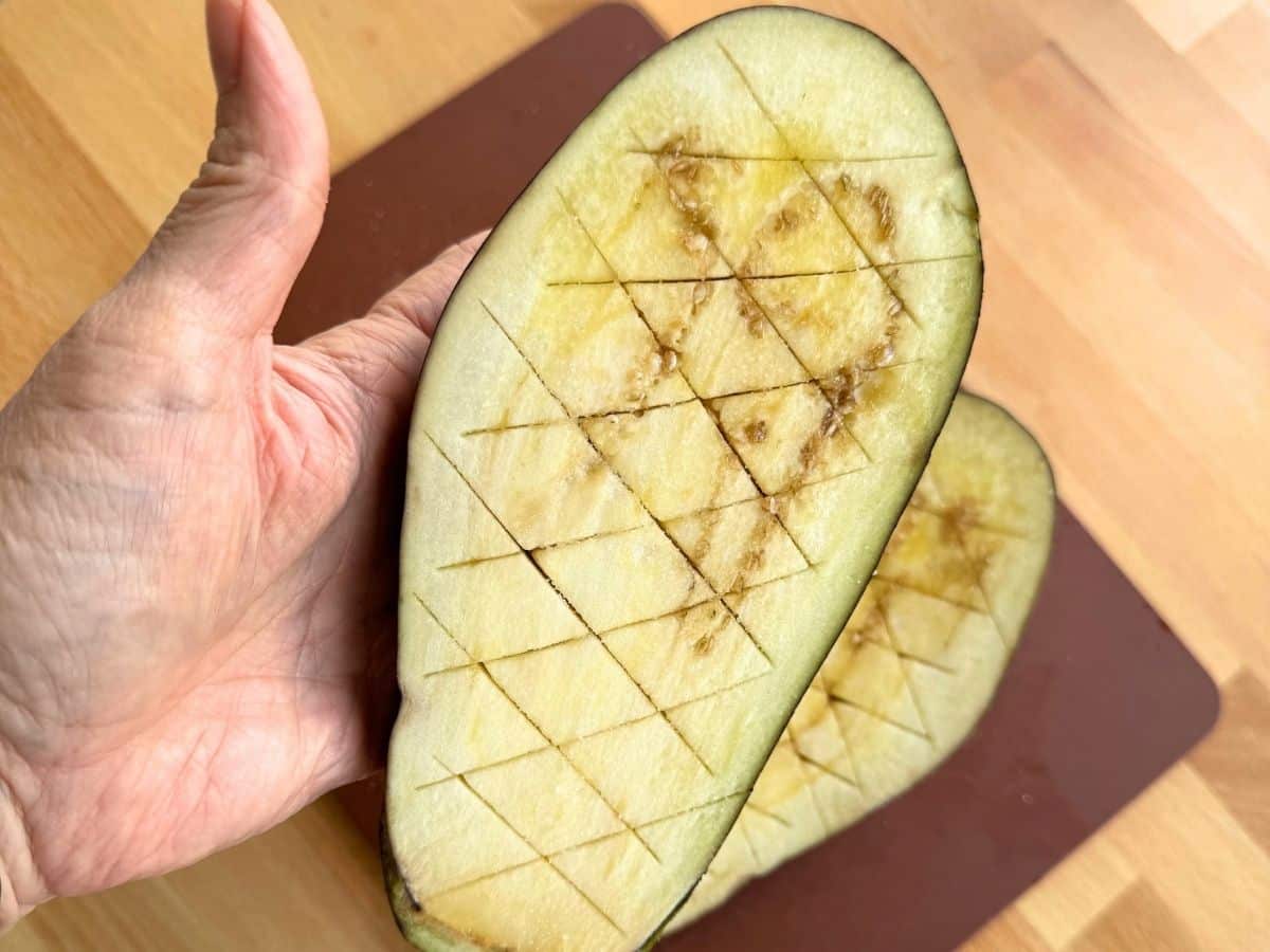 Halved eggplant scored in a crosshatch pattern for eggplant Parmesan dip.