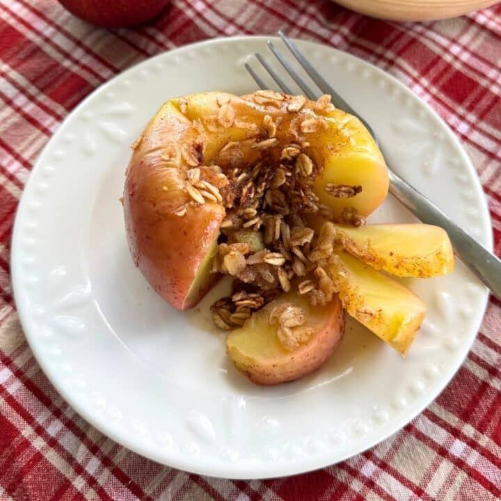 Microwave baked apple stuffed with cinnamon, oats and honey with several tender slices cut in front to expose filling.