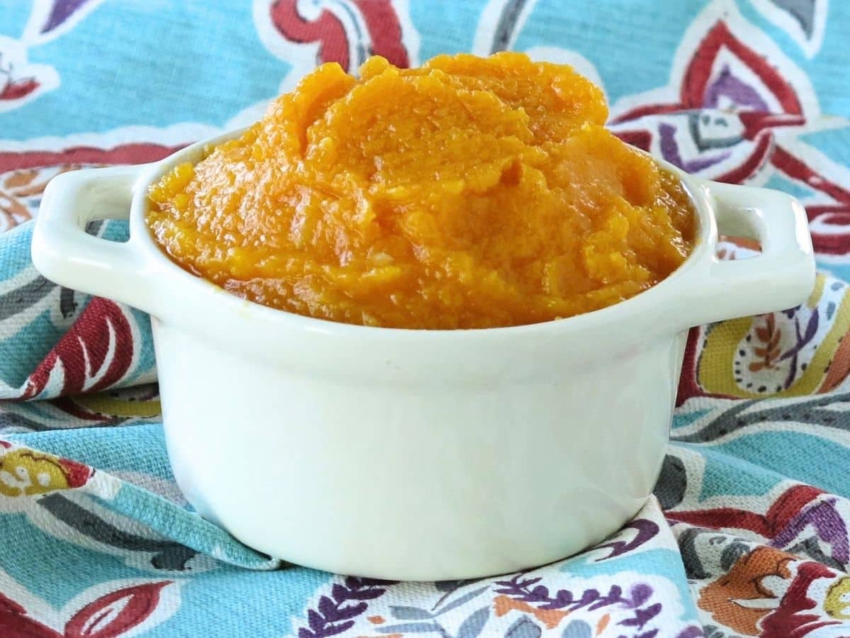 Pureed butternut squash in a white crock.