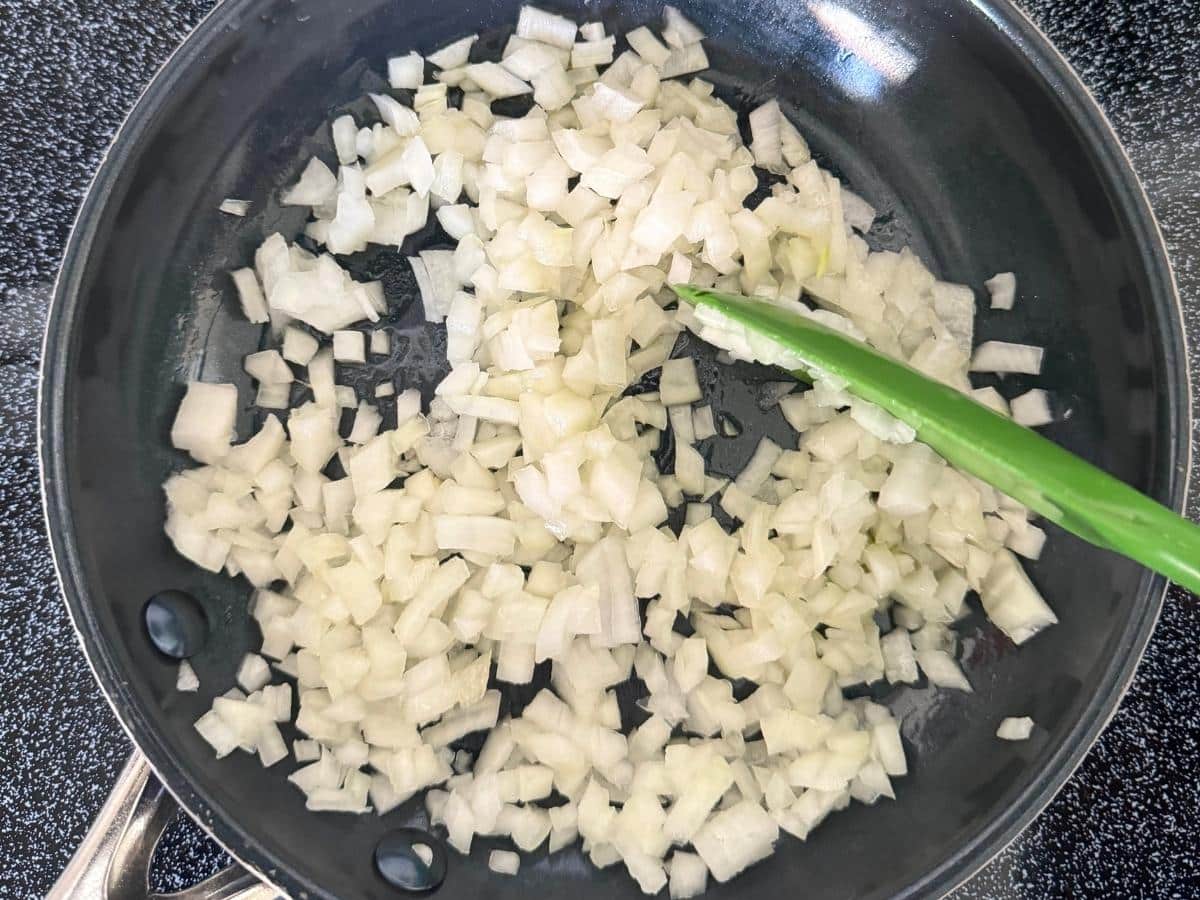 Diced onions sautéing in a skillet for spaghetti squash au gratin.