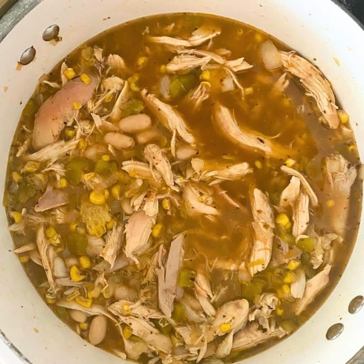 Shredded chicken, white beans, corn, and green chiles simmering in chicken broth.