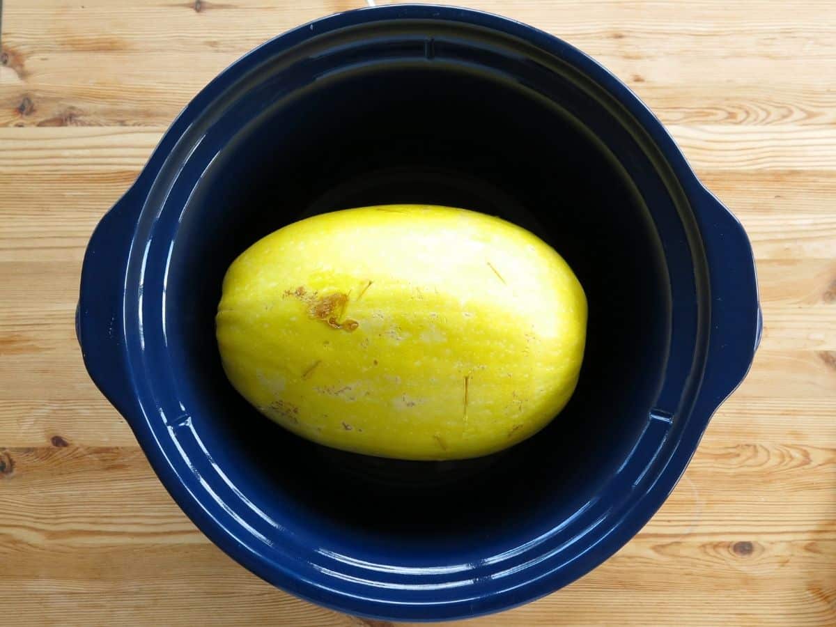 A whole spaghetti squash in a slow cooker.