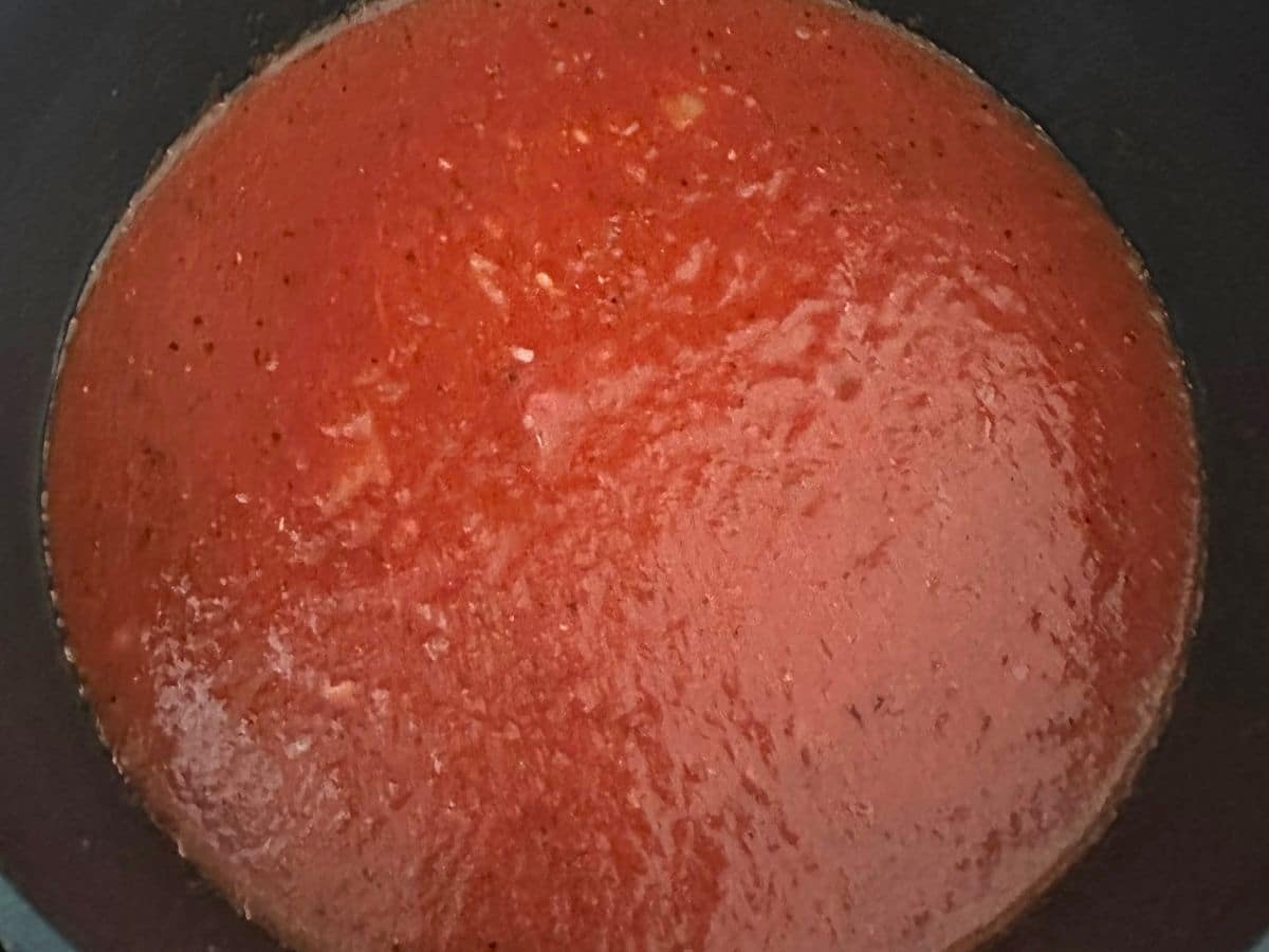 Crushed tomatoes and vegetable broth combined with sautéed onions and seasonings in a pot to make tomato Florentine soup.