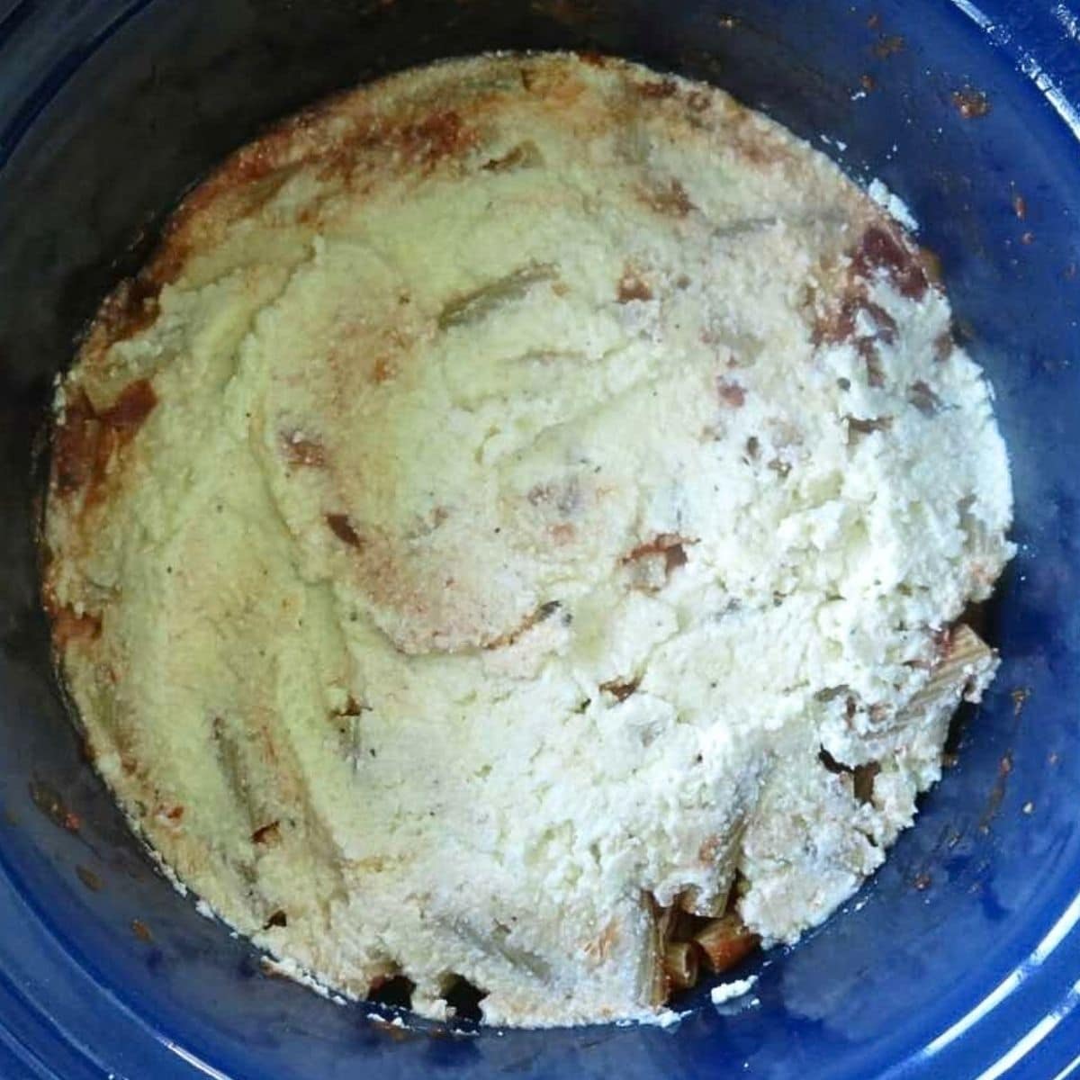 Ricotta cheese mixture spread over the first layer of pasta and marinara in the crockpot.
