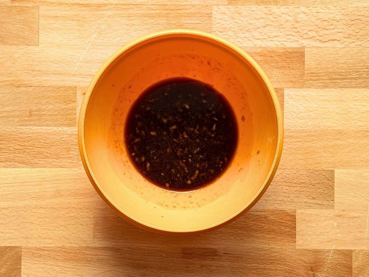 Homemade ginger soy stir fry sauce with soy sauce, brown sugar, minced garlic, and fresh ginger mixed in an orange bowl.